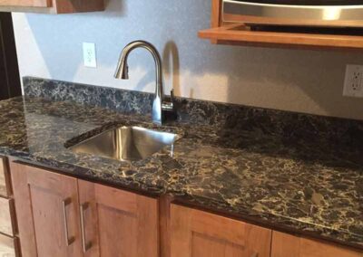Ktichen sink with granite counter and brown cabinets